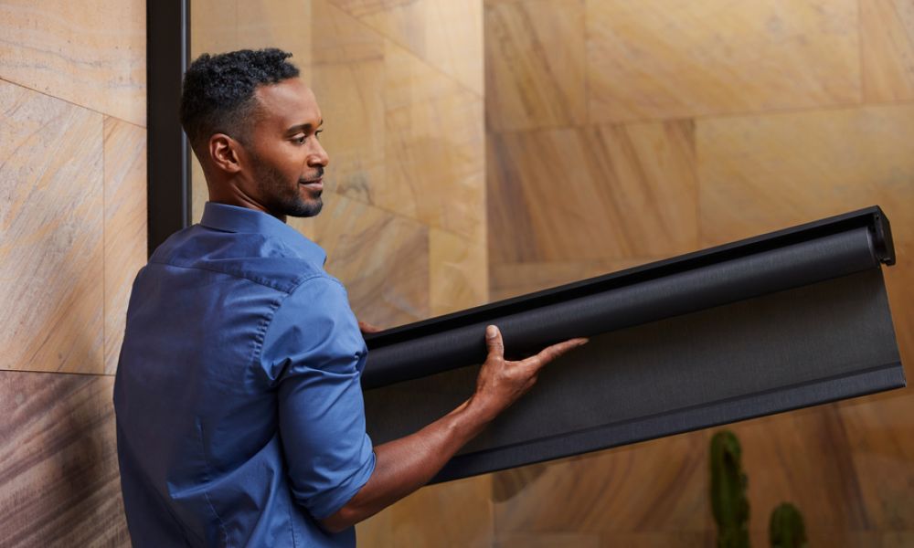 <span class="uk-h4">Savant shading installer holding a Savant roller shade to install in a luxury home.</span>