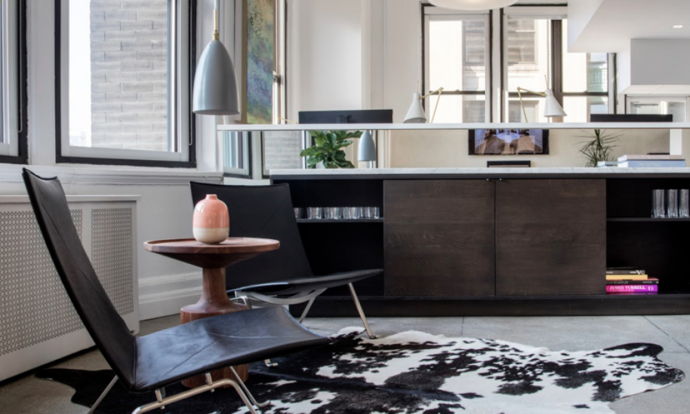 <span class="uk-h4">Sitting area with black leather chairs, cowhide rug, and natural light enhancing interior design details.</span>