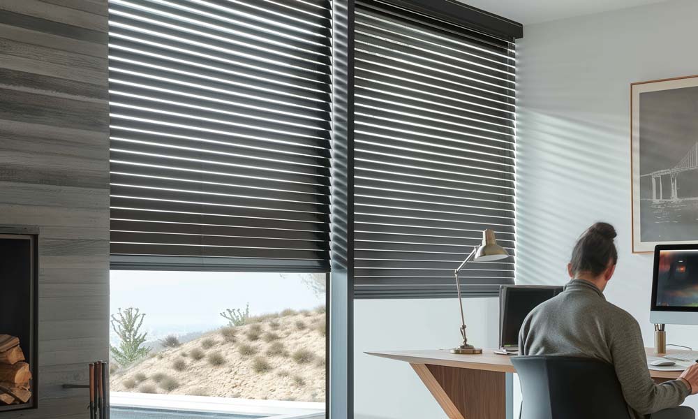 Woman working at desk with horizontal blinds filtering sunlight