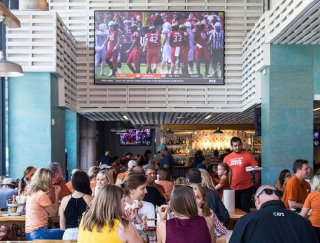 A busy restaurant with two displays, including a Screen Innovations Zero Edge Pro TV.