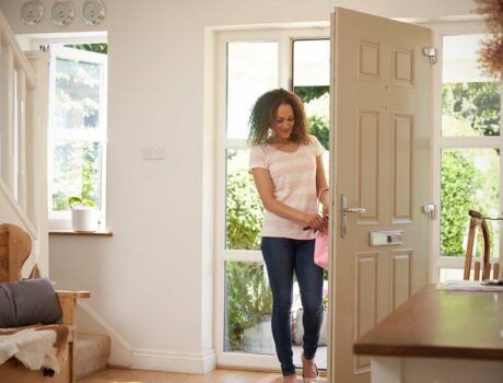 A woman in the doorway of her home, with her hands on the smart door lock.