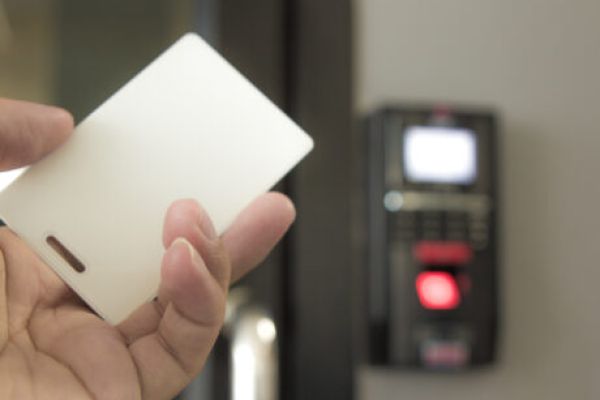 A hand holding a key card with an access control system displayed in the background.