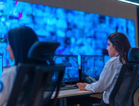 Two people monitoring security cameras.