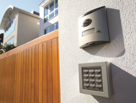 An exterior of a home with a smart home alarm and keypad on the wall in focus.