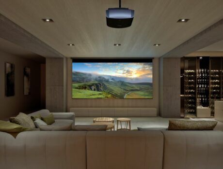 A casual home theater with a large screen, Sony projector, sectional, and wine bar.