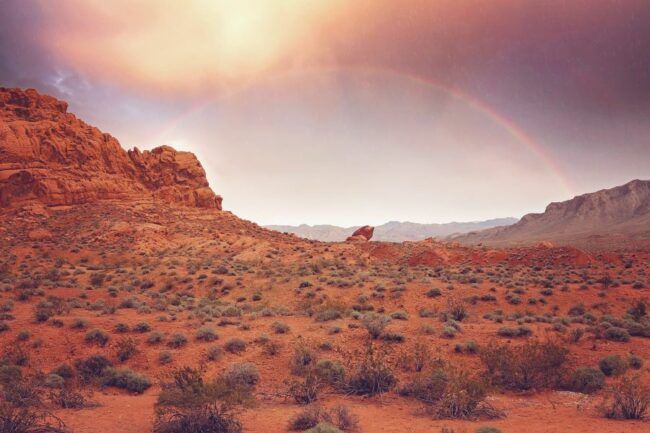 A rainbow and sunlight over a desert.