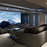 A home theater with chaise lounges, a Sony projector, and a large movie screen.