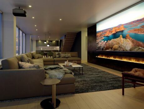 A casual home theater with a sectional, Sony projector, and large movie screen above a lit fireplace.