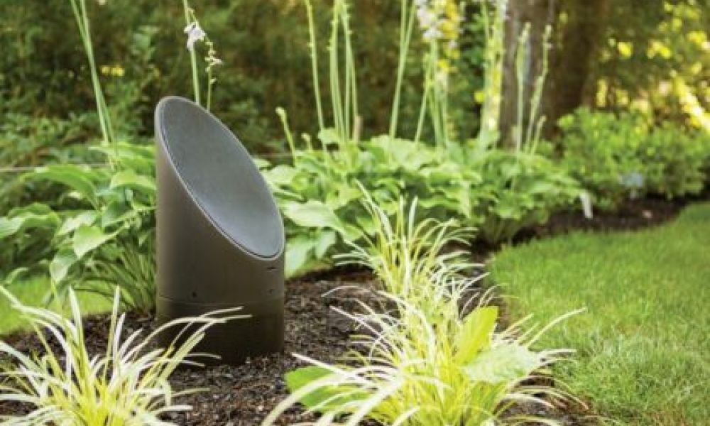 <span class="uk-h4">A Coastal Source outdoor speaker among foliage in a backyard.</span>