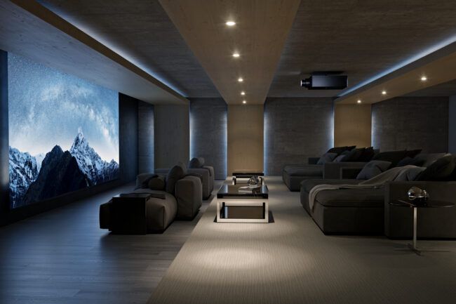 A home theater with a large movie screen depicting snow-capped mountains, a Sony projector, and chaise lounges.