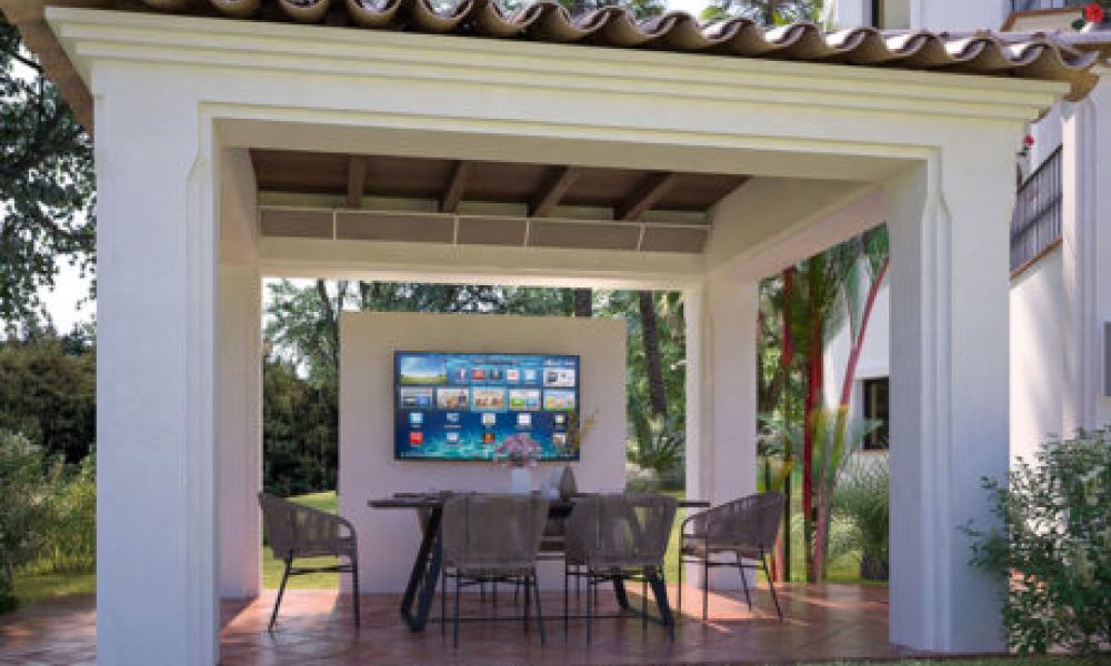 <span class="uk-h4">wall-mounted Coastal Source Razor speakers near an outdoor pergola with a TV and chairs underneath</span>