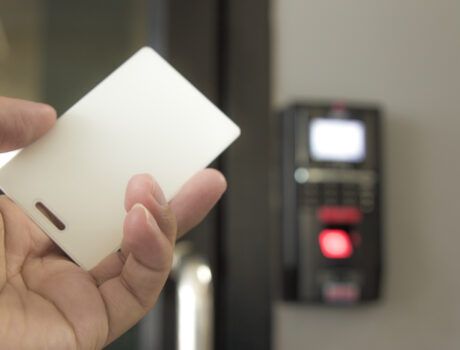 A hand holding a key card with an access control system displayed in the background.