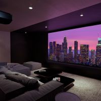 Stylish home theater with a large projection screen displaying a vibrant cityscape at sunset, featuring a cozy sectional sofa, a modern coffee table, and dim ambient lighting.