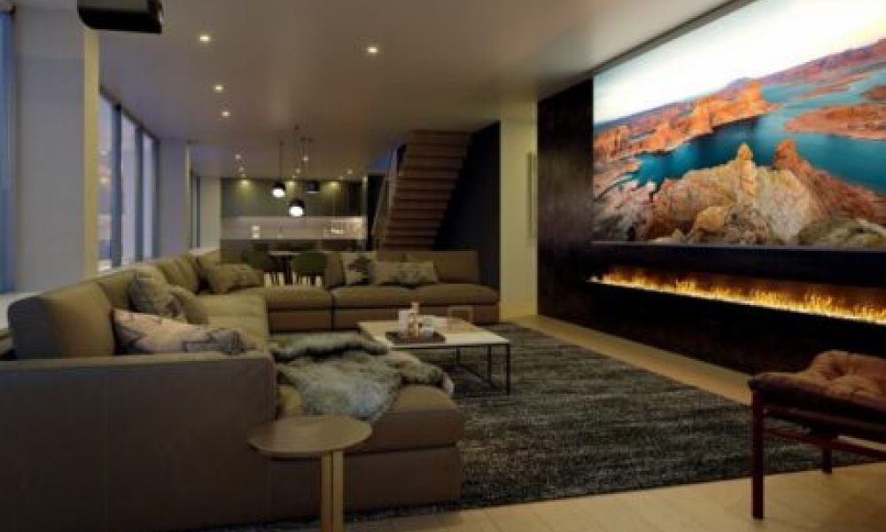 <span class="uk-h4">A casual home theater with a sectional, Sony projector, and large movie screen above a lit fireplace.</span>