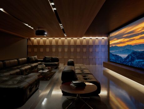 A casual home theater with a sectional, acoustic paneling, Sony projector, and large movie screen.