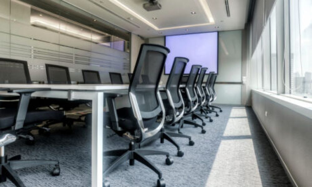 <span class="uk-h4">Corporate boardroom with a long conference table, ergonomic chairs, large windows, and a projector screen</span>